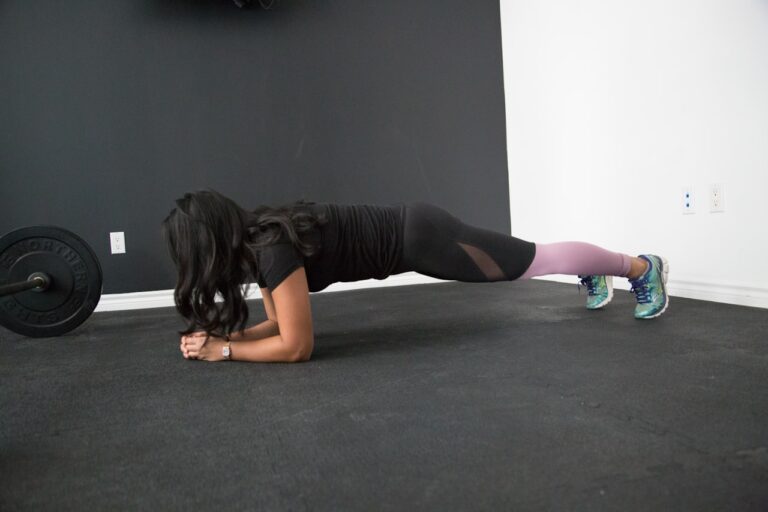 Femme en position de planche réalisant un exercice de gainage en salle de sport
