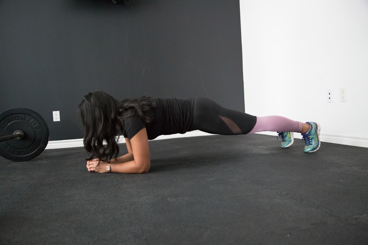 Femme en position de planche réalisant un exercice de gainage en salle de sport
